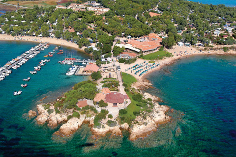 Vista aérea del complejo vacacional Centro Vacanze Isuledda en Cerdeña, Italia, con playas y puerto deportivo.