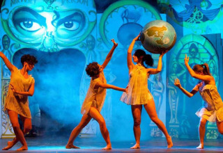 Cuatro bailarinas actúan en el escenario con un globo terráqueo en Centro Vacanze Isuledda, Cerdeña, Italia.