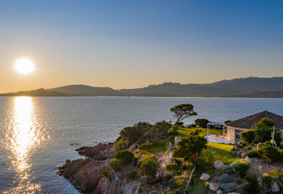 Solnedgang over havet ved Centro Vacanze Isuledda, en feriepark på Sardinien med kystudsigt og villa.
