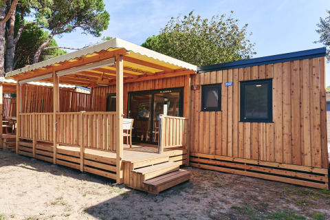 Vue extérieure de la SunLodge Sabai avec terrasse en bois couverte, entourée d'arbres en pleine nature.