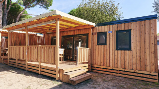 Exterior de SunLodge Sabai con terraza de madera techada, rodeado de árboles en un entorno natural agradable.