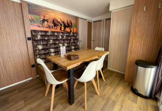 Coin repas moderne à SunLodge Sabai avec table en bois, chaises blanches, décor éléphants et sol en bois.