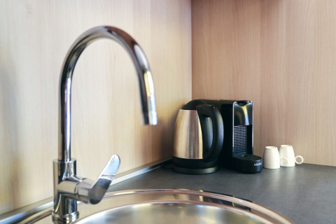 Grifo moderno, hervidor, cafetera y tazas sobre la encimera de la cocina en SunLodge Sabai.
