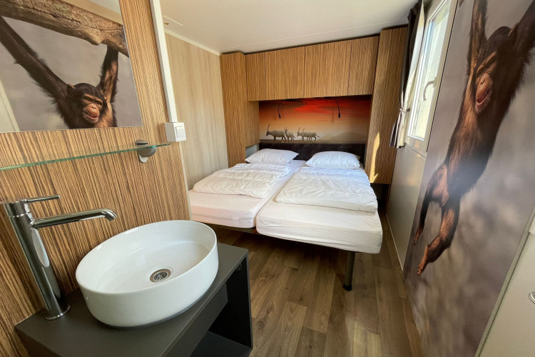 Habitación en SunLodge Sabai con dos camas, lavabo, decoración de madera y murales de monos y animales.