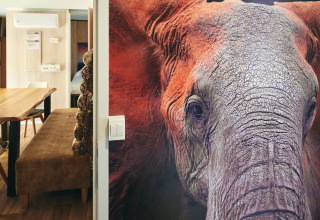 Grande fresque murale d'éléphant au SunLodge Sabai, intérieur moderne et coin repas en arrière-plan.