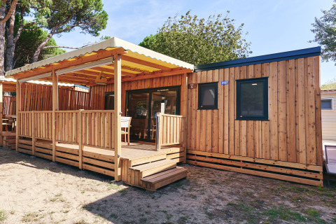 Vista exterior de SunLodge Babul en Centro Vacanze Isuledda, Italia, con terraza de madera cubierta.