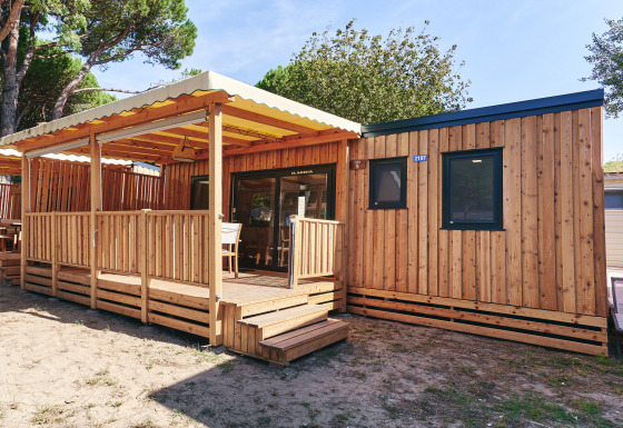 Vista exterior de SunLodge Babul en Centro Vacanze Isuledda, Italia, con terraza de madera cubierta.