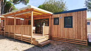 Vista exterior de SunLodge Babul en Centro Vacanze Isuledda, Italia, con terraza de madera cubierta.