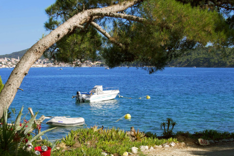 Vista sul mare con barche al Camping Village Poljana nella contea di Primorje-Gorski Kotar, Croazia, tra gli alberi.