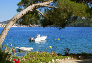 Vista sul mare con barche al Camping Village Poljana nella contea di Primorje-Gorski Kotar, Croazia, tra gli alberi.