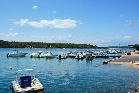 Barcos atracados en un muelle en aguas cristalinas en Camping Village Poljana, Primorje-Gorski Kotar, Croacia.