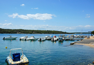 Boats moored at a dock in clear water at Camping Village Poljana, Primorje-Gorski Kotar, Croatia.