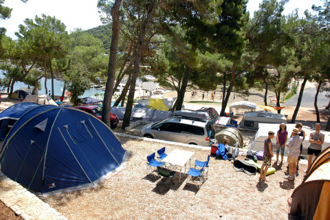 Camping Village Poljana in Croazia con tende, roulotte, persone e vista panoramica sul mare.