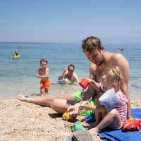 Un padre y sus hijos juegan en una playa cerca de Mali Lošinj, Croacia, en un día soleado de verano.