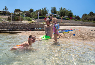 Family enjoys swimming and relaxing at the beach in Camping Village Poljana, Primorje-Gorski Kotar, Croatia.