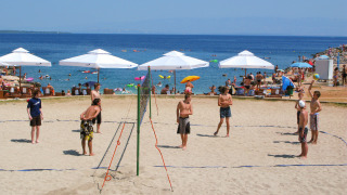 Parque vacacional en Croacia con personas jugando vóley playa en la arena junto al mar y sombrillas.