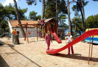 Bambini che giocano nel parco giochi del Camping Village Poljana, tra alberi e casette in Croazia.