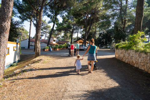 Family walks through sunlit trail at Camping Village Poljana, a holiday park in Primorje-Gorski Kotar, Croatia.
