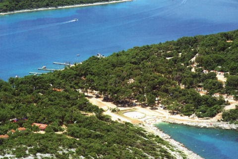 Aerial view of Camping Village Poljana, a forested holiday park beside the blue sea in Primorje-Gorski Kotar, Croatia.