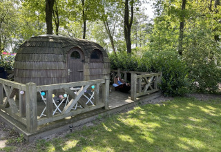 Sfeervolle IGLO Log Cabin bij Camping Emmen in Nederland, met houten terras, tafel, stoelen en hangmat.