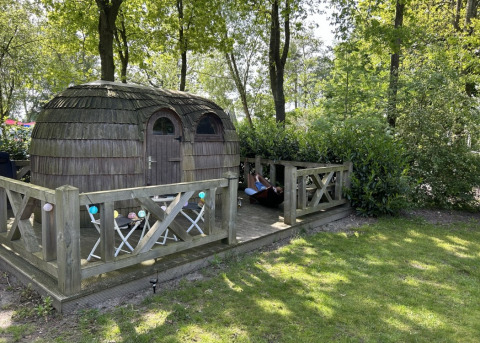Charming IGLO Log Cabin at Camping Emmen in the Netherlands, featuring a wooden deck with table, chairs, and hammock.