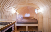 Interiør af IGLO Log Cabin på Camping Emmen i Holland, med trævægge, seng og lille køkkenhjørne.