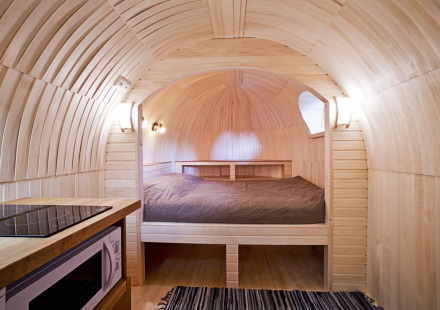 Interieur van IGLO Log Cabin op Camping Emmen in Nederland, met houten wanden, bed en kitchenette.