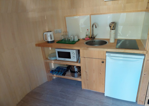 Kleine keuken in IGLO Log Cabin bij Camping Emmen, Nederland, met gootsteen, magnetron en koelkast.
