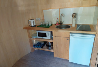 Cocina pequeña en IGLO Log Cabin del Camping Emmen, Países Bajos, con fregadero, microondas y nevera.