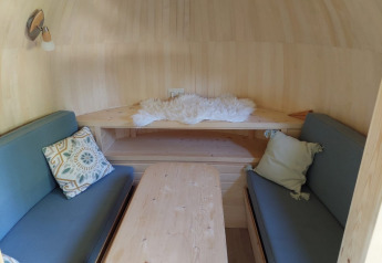 Accogliente interno della IGLO Log Cabin al Camping Emmen nei Paesi Bassi, con divani blu e tavolo in legno.