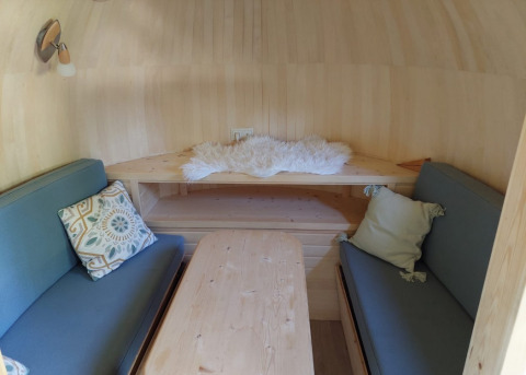 Cozy interior of IGLO Log Cabin at Camping Emmen with blue sofas, cushions, and a wooden table in the Netherlands.