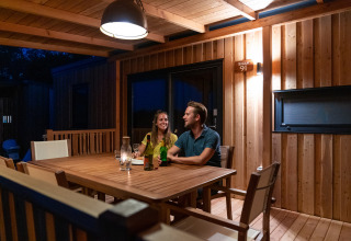 Pareja disfrutando la noche en la terraza de madera de SunLodge BigLeaf, sentada con bebidas.