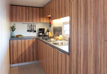 Moderne keuken in SunLodge BigLeaf met houtlook kasten, fornuis, spoelbak en ophangend keukengerei.