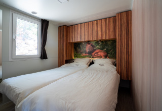 Dormitorio en SunLodge BigLeaf con dos camas individuales, paneles de madera y una imagen de león.