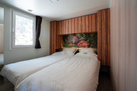 Dormitorio en SunLodge BigLeaf con dos camas individuales, paneles de madera y una imagen de león.
