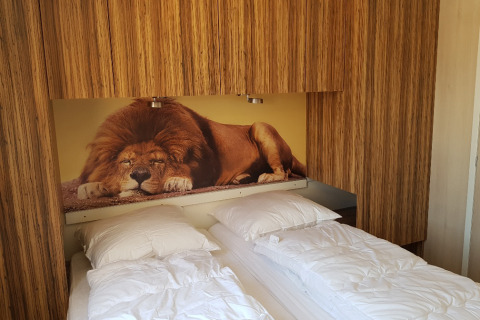 Dormitorio en SunLodge BigLeaf con dos camas individuales y un gran mural de león como cabecera.