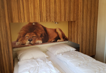 Dormitorio en SunLodge BigLeaf con dos camas individuales y un gran mural de león como cabecera.