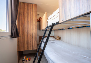 Chambre avec lits superposés moderne au SunLodge BigLeaf, jouets, placards en bois et lumière naturelle.