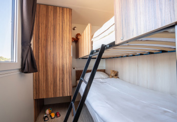 Moderne stapelbedkamer in SunLodge BigLeaf met speelgoed, houten kasten en veel daglicht via het raam.