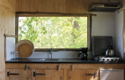 Boomhutkeuken met groot raam en uitzicht op bomen in Treehouse at Beloofde Land, Nederland.