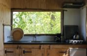 Træhuskøkken med stort vindue og udsigt over grønne træer i Treehouse at Beloofde Land, Holland.