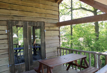 Boomhut veranda met houten tafel en banken tussen het groen, Beloofde Land, Nederland.