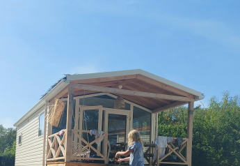 To børn leger i mudderet foran et sommerhus på Beloofde Land i Holland under en klar blå himmel.