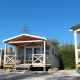 Tre strandhuse af træ ved naturhuset Beach House med veranda under en klar blå himmel om dagen.
