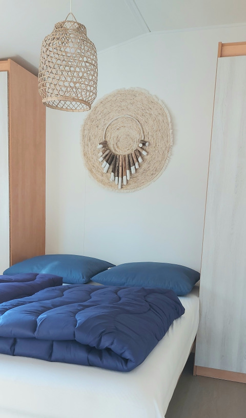Modernes Schlafzimmer im Beach House am Beloofde Land, Niederlande, mit blauer Bettwäsche und Korbdekoration.