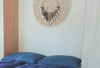 Camera moderna al Beach House nel Beloofde Land, Paesi Bassi, con biancheria blu e decoro intrecciato a parete.