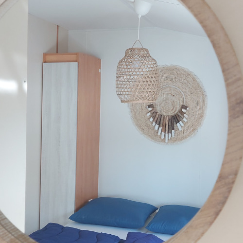 Spejlbillede af et hyggeligt værelse i Beach House på Beloofde Land, med blå puder og naturlig indretning.