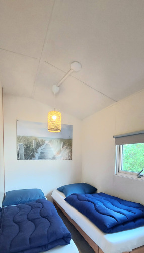 Lyst værelse i Beach House, Beloofde Land, Holland, med to senge, blå sengetøj og vindue.