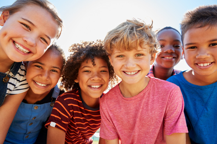 Un grupo de niños sonrientes posa al aire libre en un alojamiento de glamping durante el día.