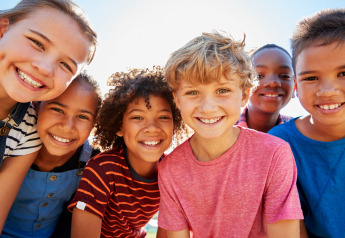 Un grupo de niños sonrientes posa al aire libre en un alojamiento de glamping durante el día.